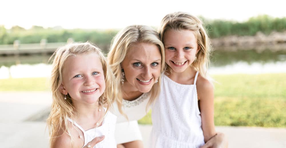 Dr. Carmouche poses with her young daughters in matching white dresses.