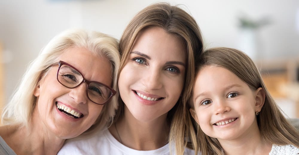 Three generations of dental patients smile happily.